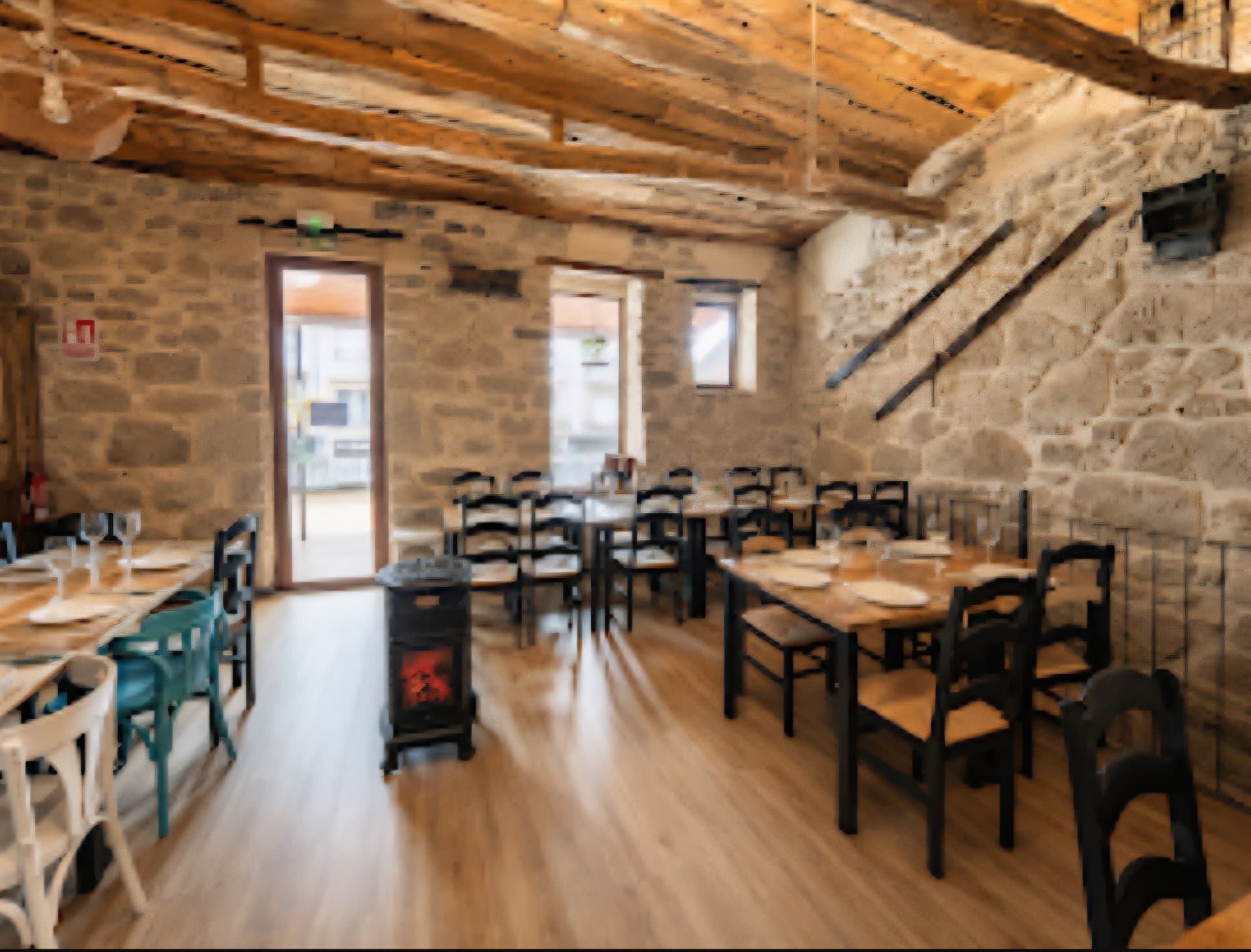 Sala principal del restaurante con paredes de piedra, vigas de madera y mesas preparadas